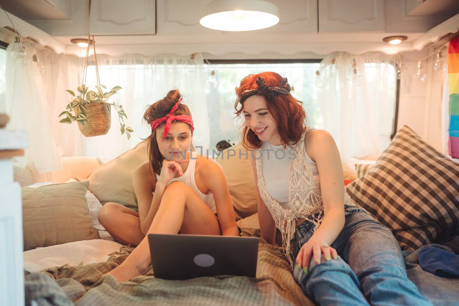 Portrait of a cute lesbian couple. Two girls spend time tenderly together watching movie on laptop in a camper trailer. Love and attitude. LGBT concept. High quality photo