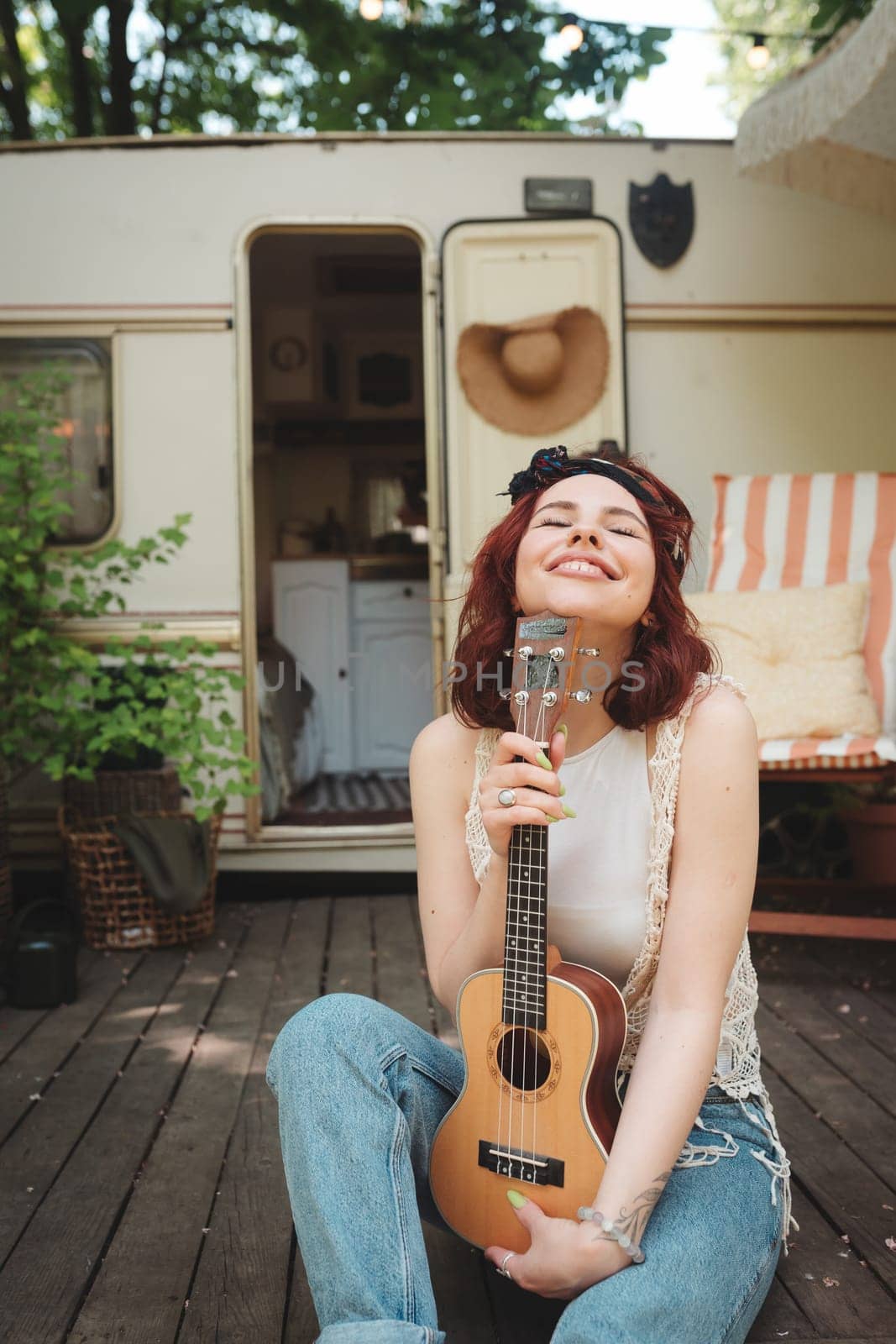 Happy hippie girl are having a good time with playing on guitar in camper trailer. Holiday, vacation, trip concept.High quality photo