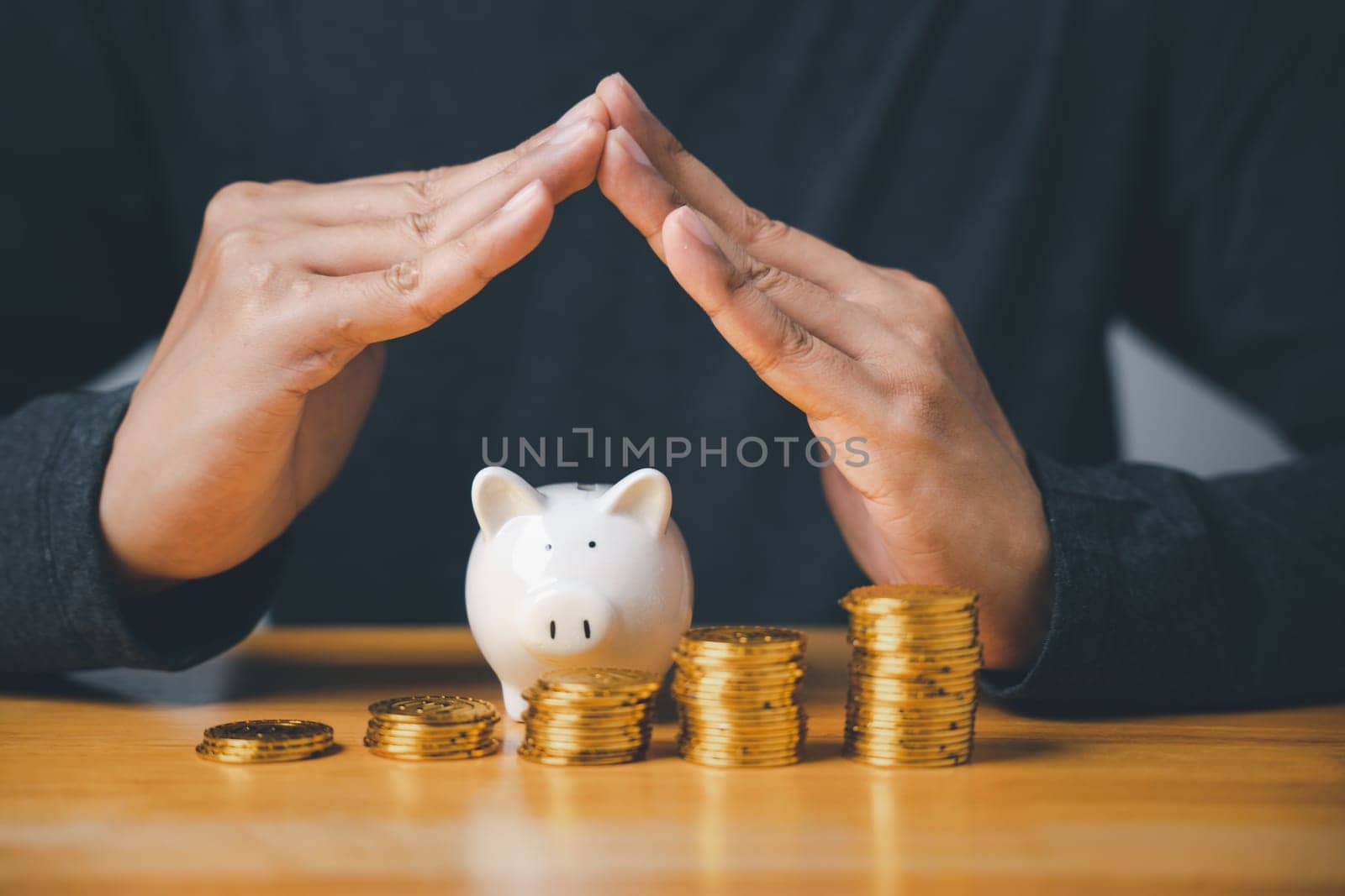 A man holding piggy bank and stacks of coins by Sorapop
