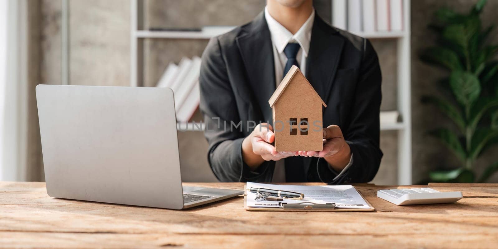 A real estate agent holding a small new house in her hands.
