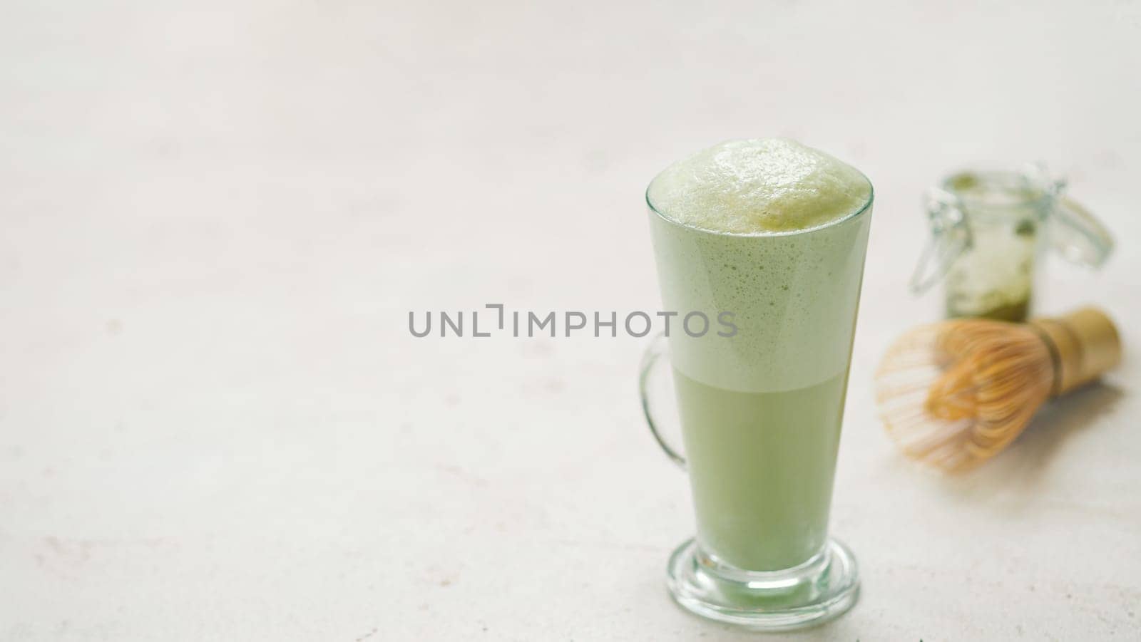 Matcha green tea latte in glass. Matcha latte on light background. Copy space. Banner