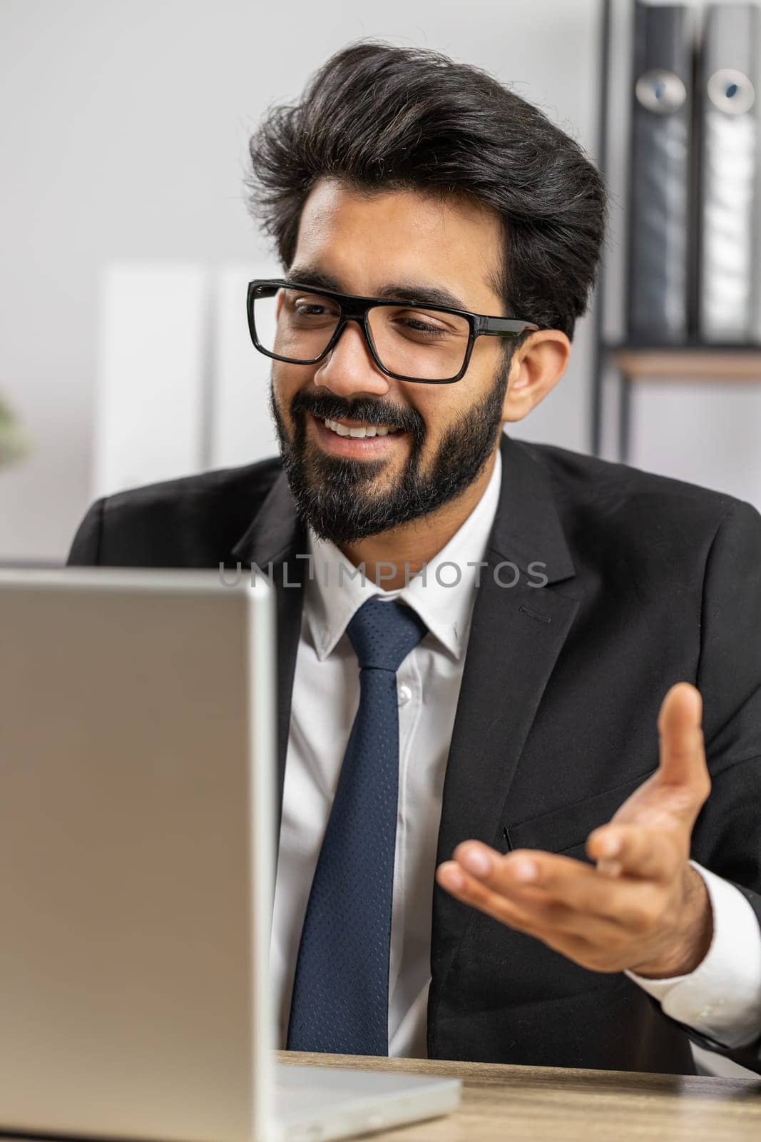 Indian businessman working on laptop computer at home office desk talk on online communication video call with employee, boss. Manager man freelancer support services looking at webcam of computer