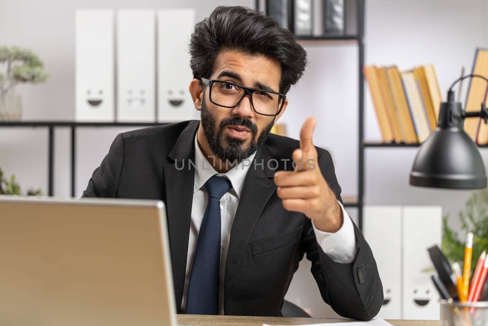 I choose you. Young indian businessman programmer software developer working on office laptop pointing to camera, looking with happy expression, making choice, showing direction. Arab freelancer man