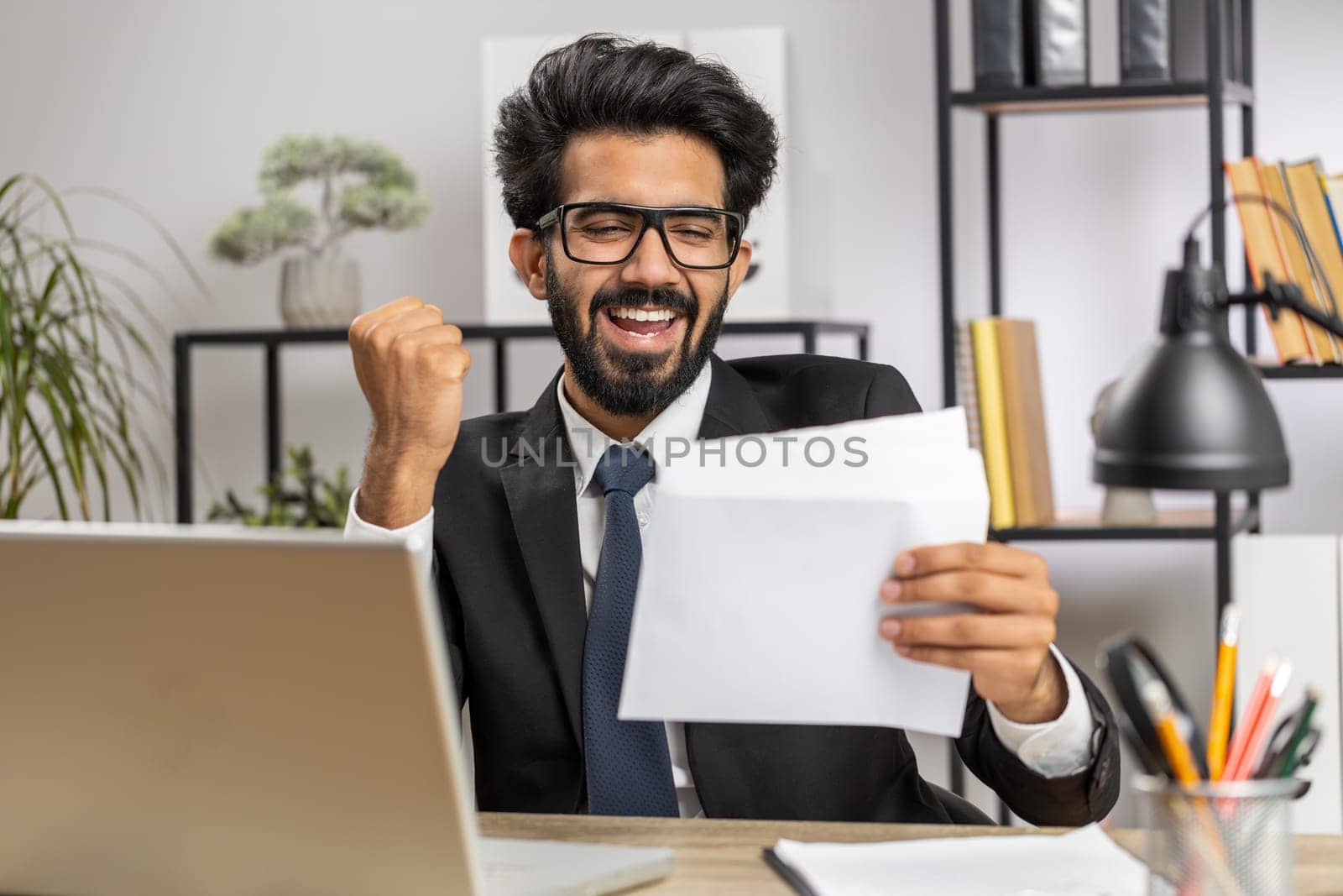 Indian business man open envelope letter, reading it. Career growth advance promotion, bank loan approve, successful admission to monetary award, long-awaited invitation, great news, lottery game win