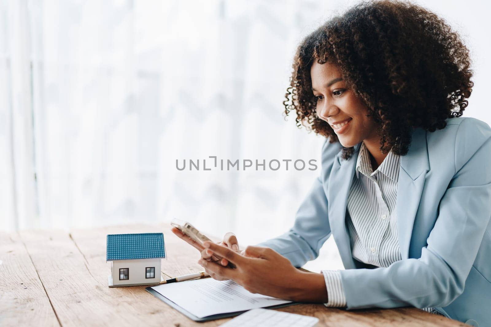 Real estate agent, African American businesswoman Africans use smartphone and calculators to offer mortgages to their clients. Home mortgage and insurance finance concepts.