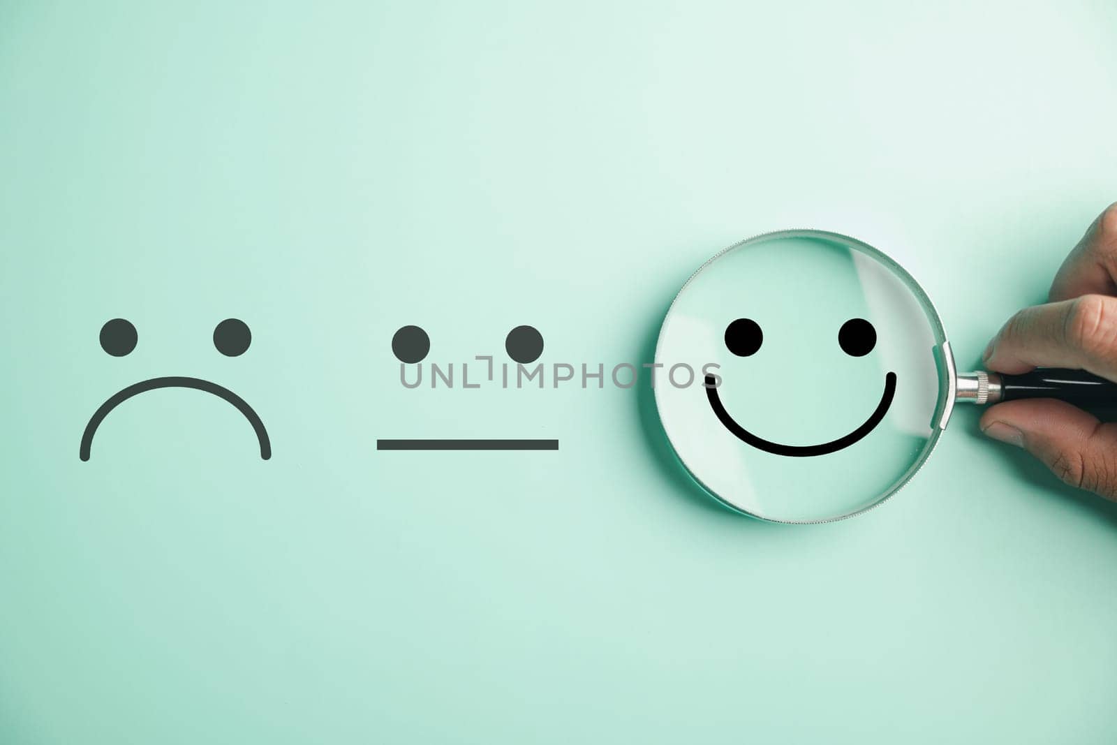 Magnifier in hand focuses on selected happy smiley face icon by Sorapop