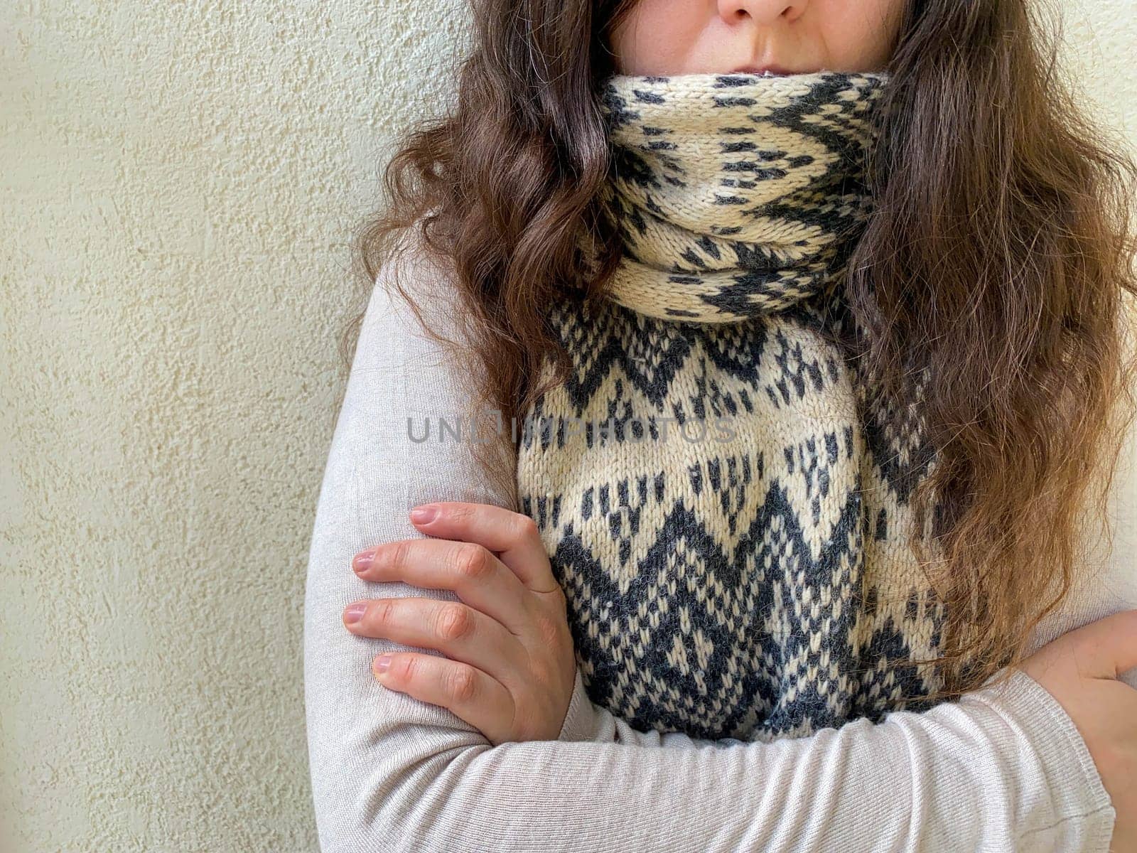 Woman in scarf and turtleneck, cold weather, no heating. Young woman with curly dark hair wearing a turtleneck and scarf.