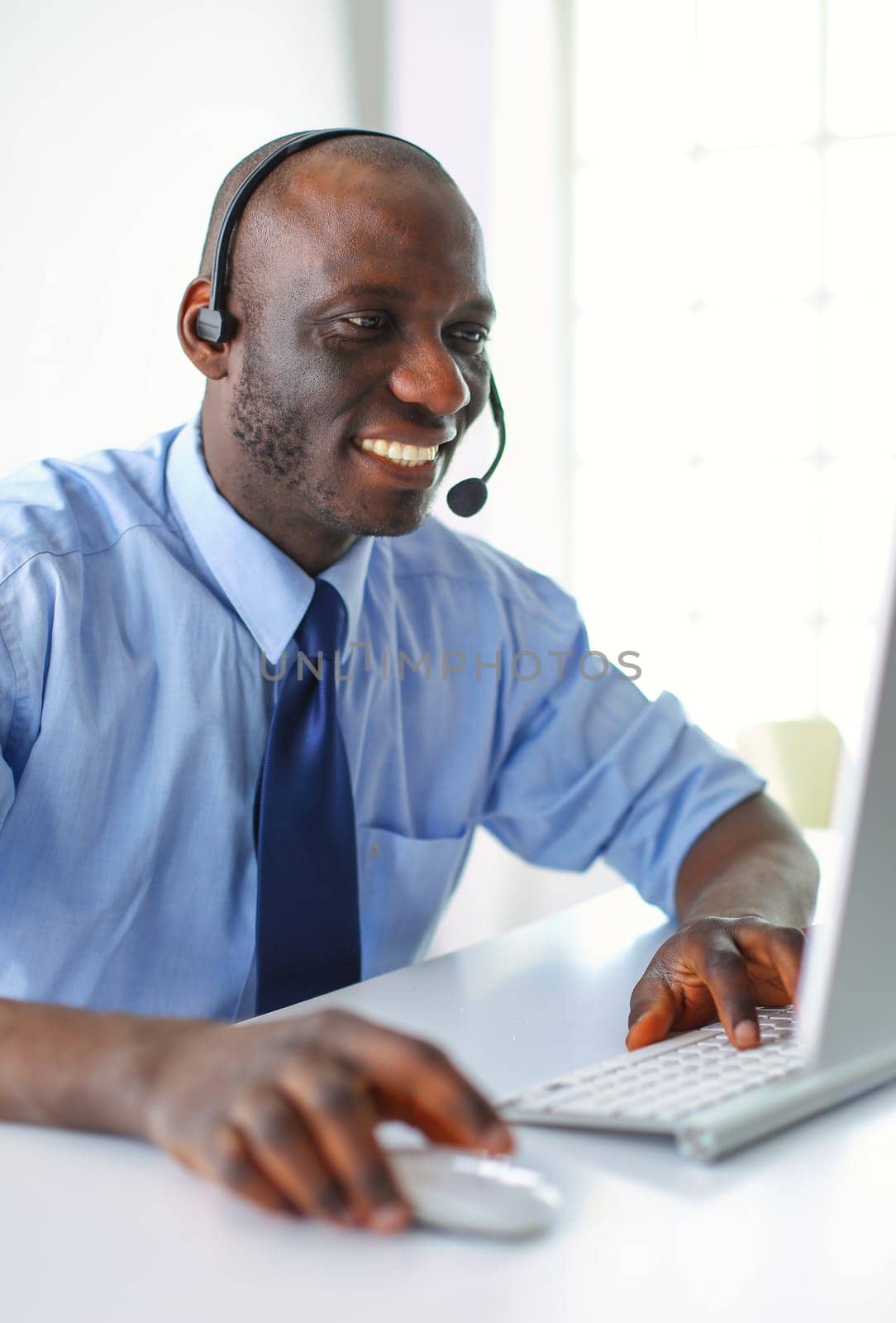 African american businessman on headset working on his laptop by lenets