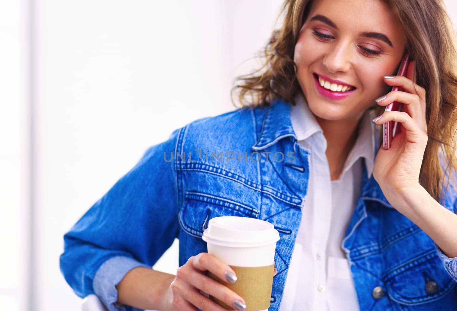 Young woman at cafe drinking coffee and talking on the mobile phone