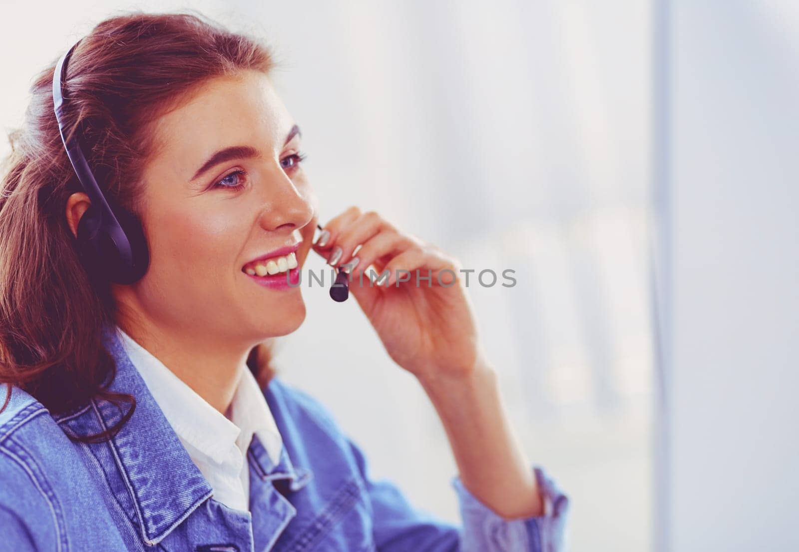 Portrait of beautiful business woman working at her desk with headset and laptop by lenets