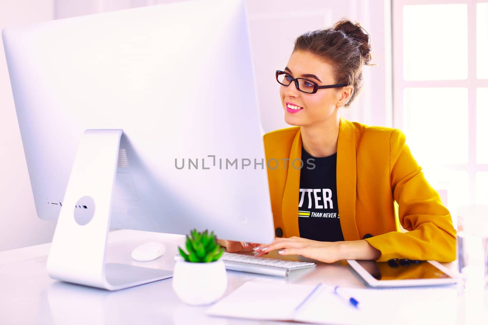 Young confident businesswoman working at office desk and typing with a laptop.