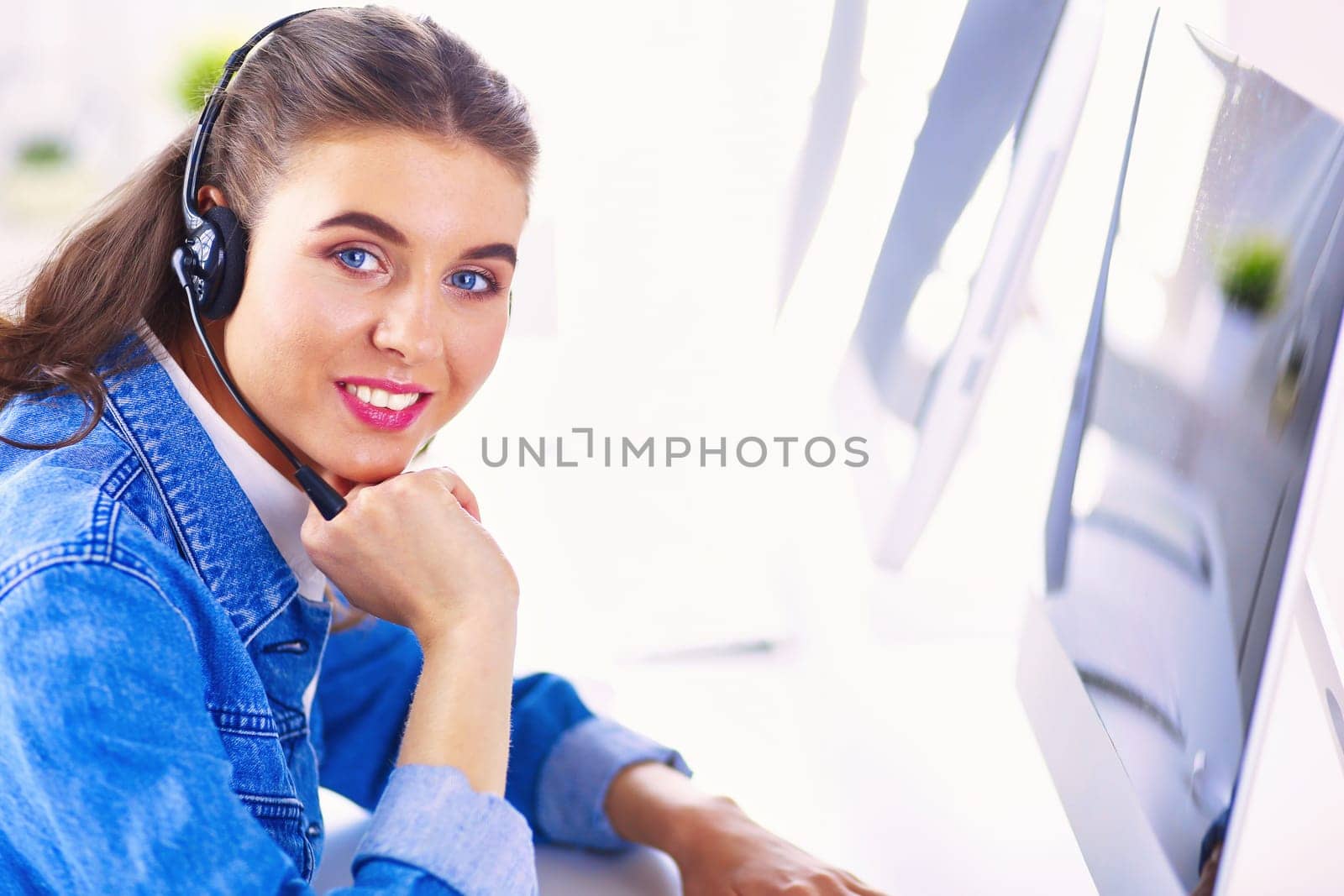 Portrait of beautiful business woman working at her desk with headset and laptop.