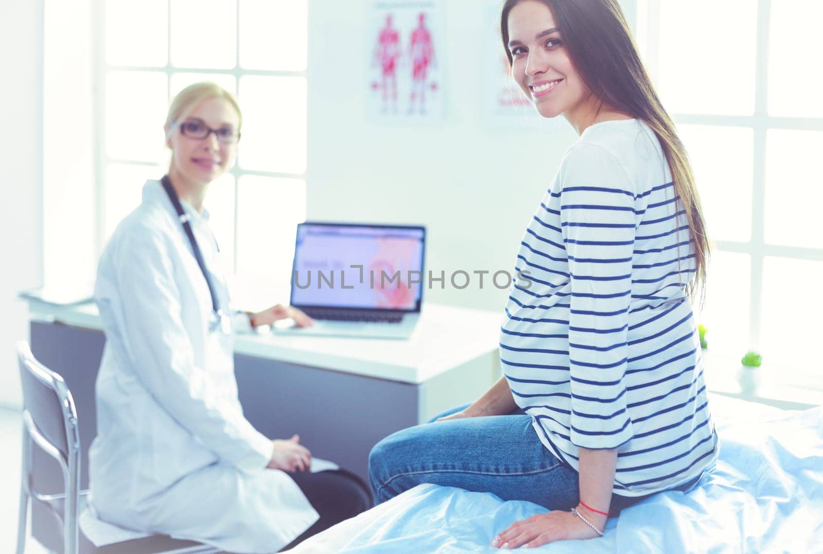 Beautiful smiling pregnant woman with the doctor at hospital.