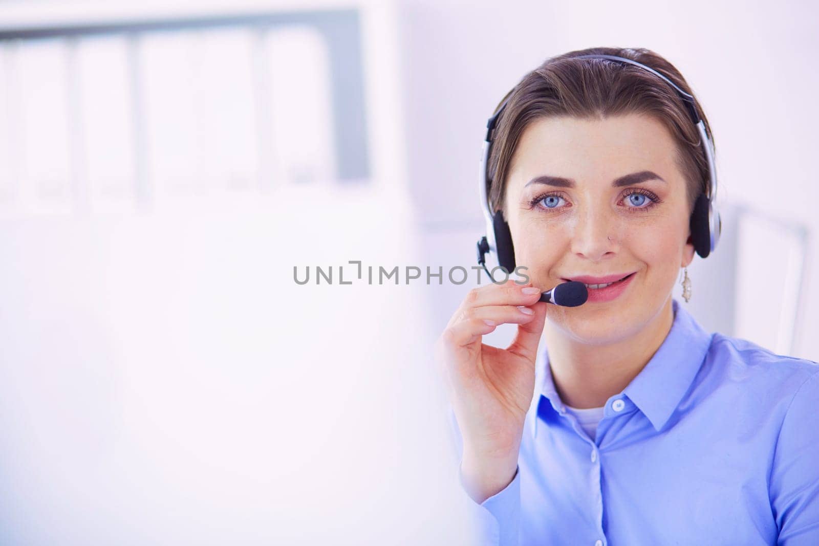 Serious pretty young woman working as support phone operator with headset in office.