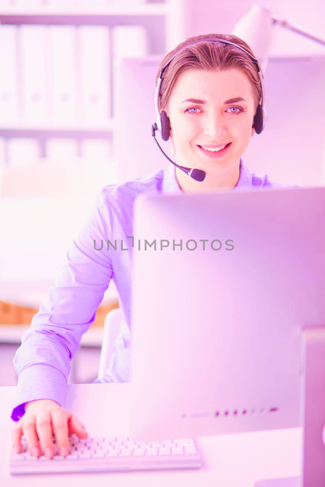 Serious pretty young woman working as support phone operator with headset in office.