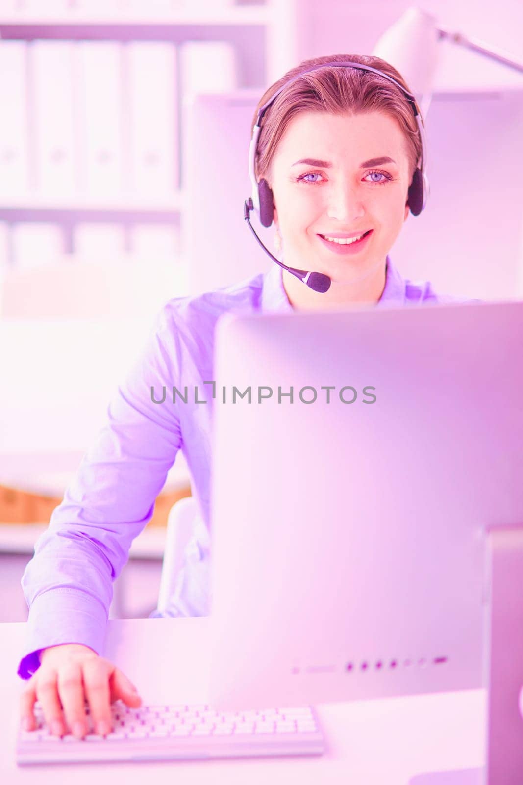 Serious pretty young woman working as support phone operator with headset in office.