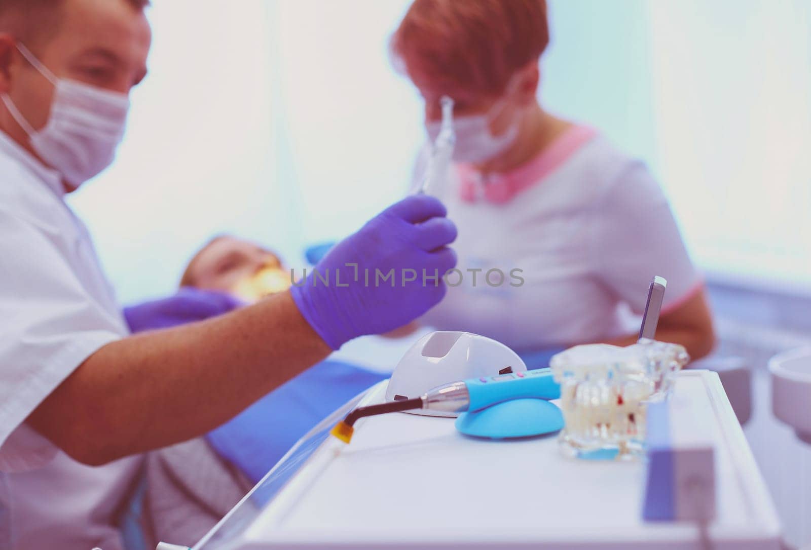 Portrait of a dentist who treats teeth of young woman patient by lenets