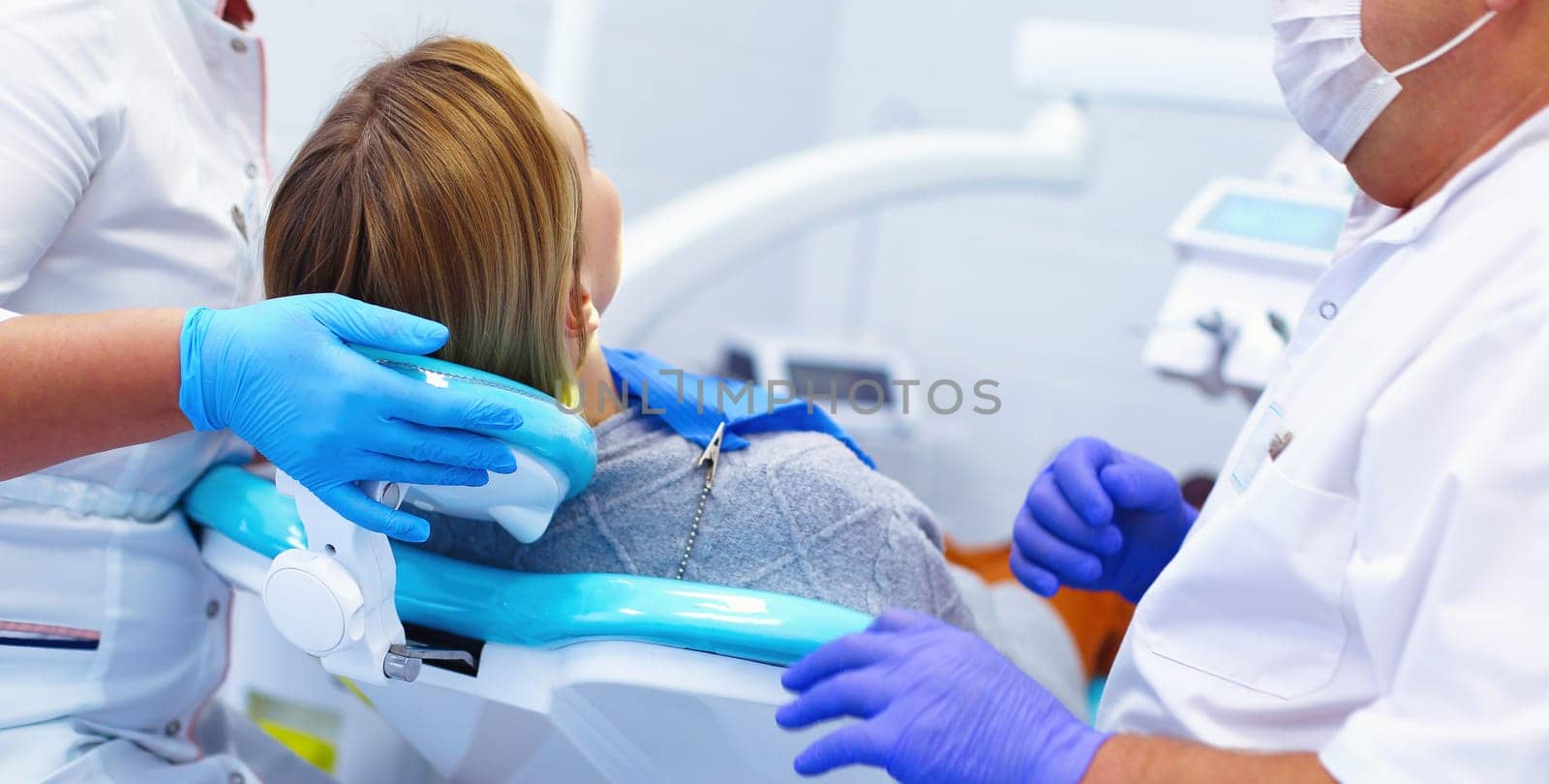 Senior male dentist in dental office talking with female patient and preparing for treatment.