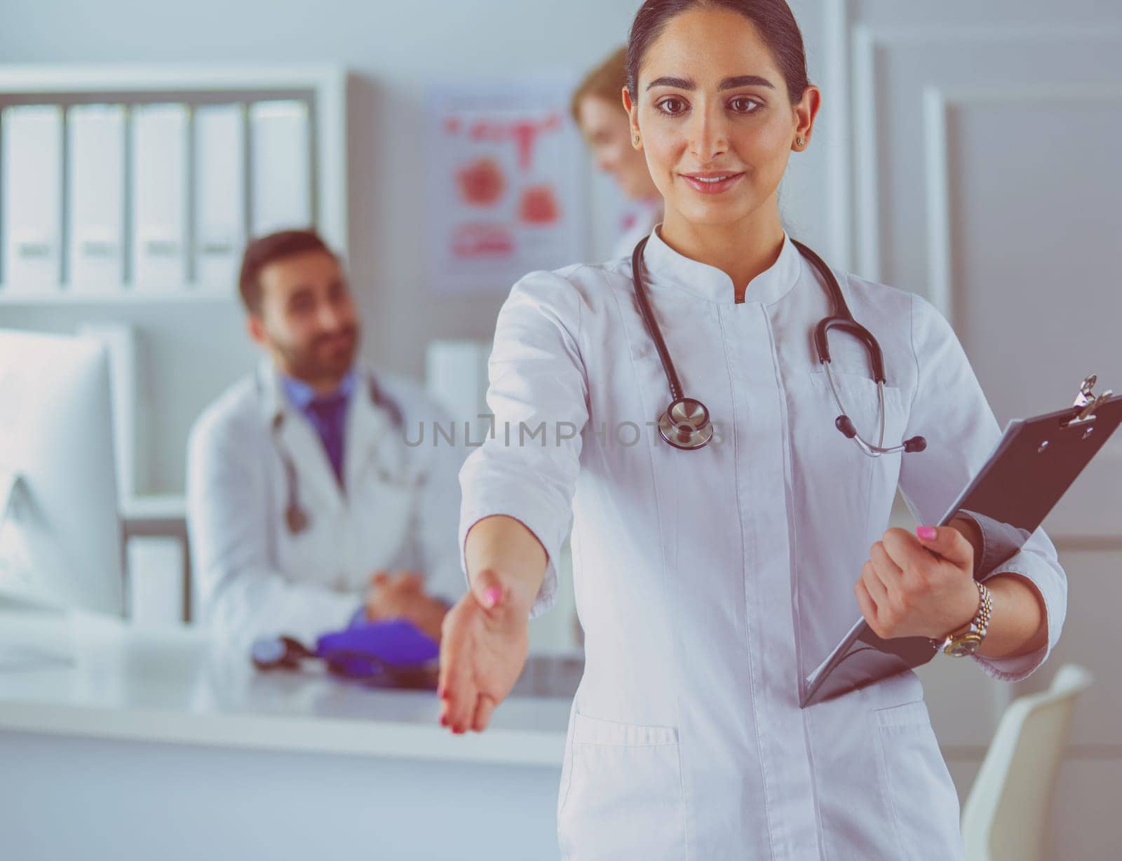 Portrait of young beautiful woman doctor giving handshake.