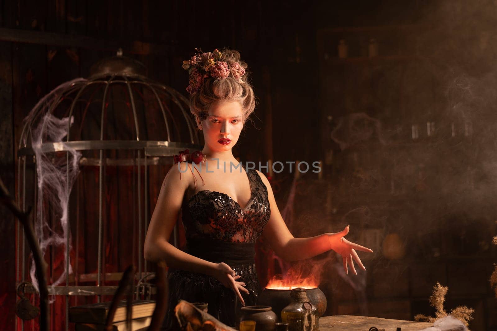 Halloween witch with cauldron. Beautiful young woman conjuring, making witchcraft. Standing spooky dungeon dark room. Enchantress prepare love potion use magic spell