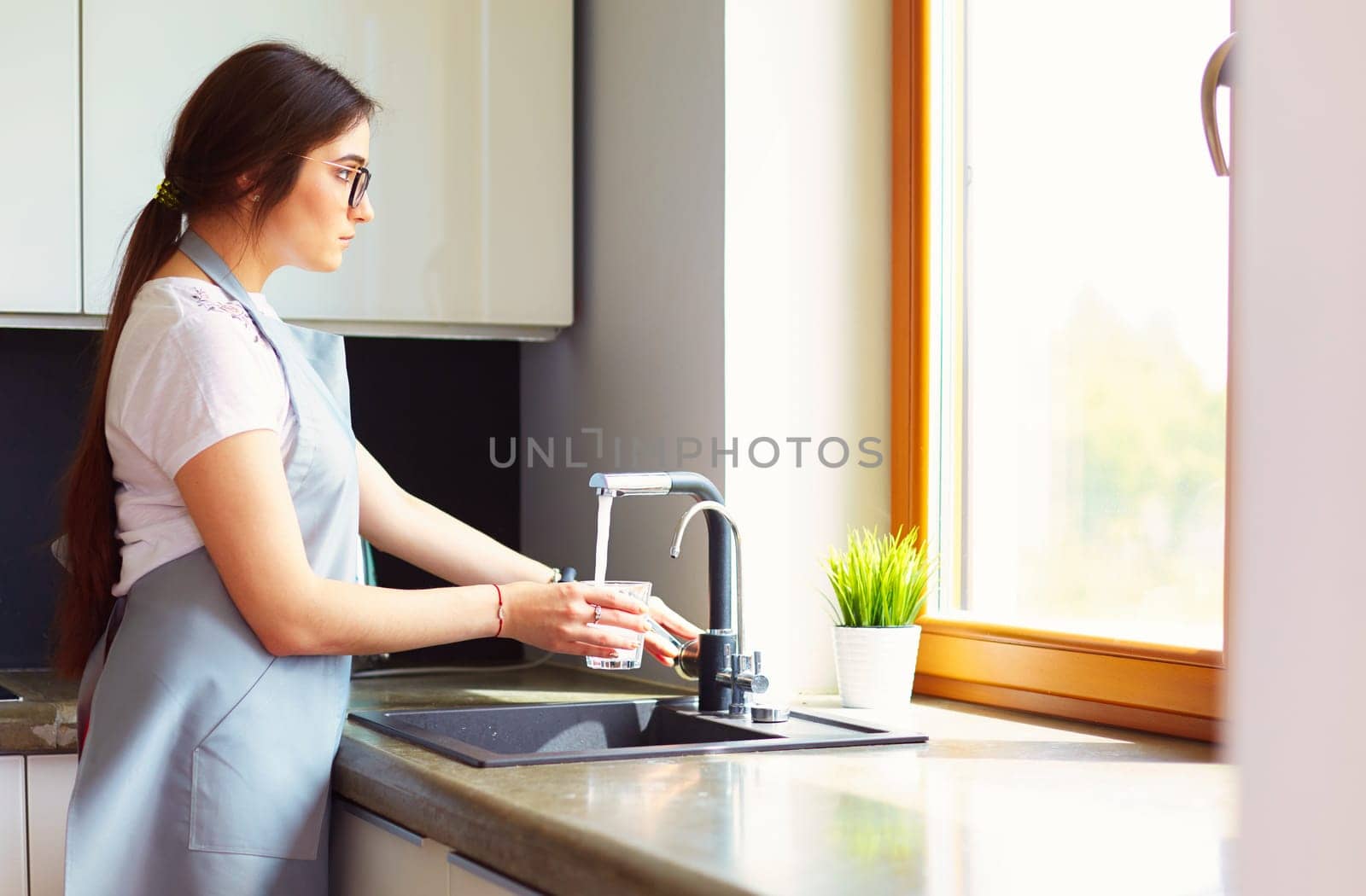 Woman hand's filling the glass of water.