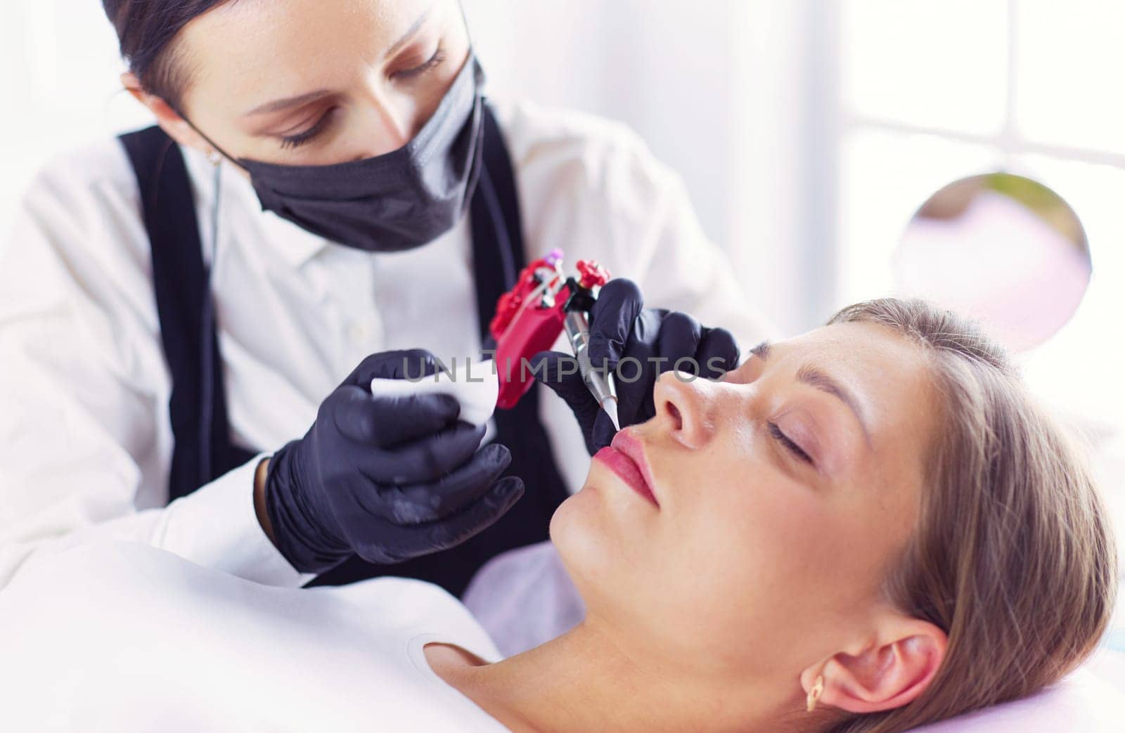 Cosmetologist applying permanent make up on eyebrows.