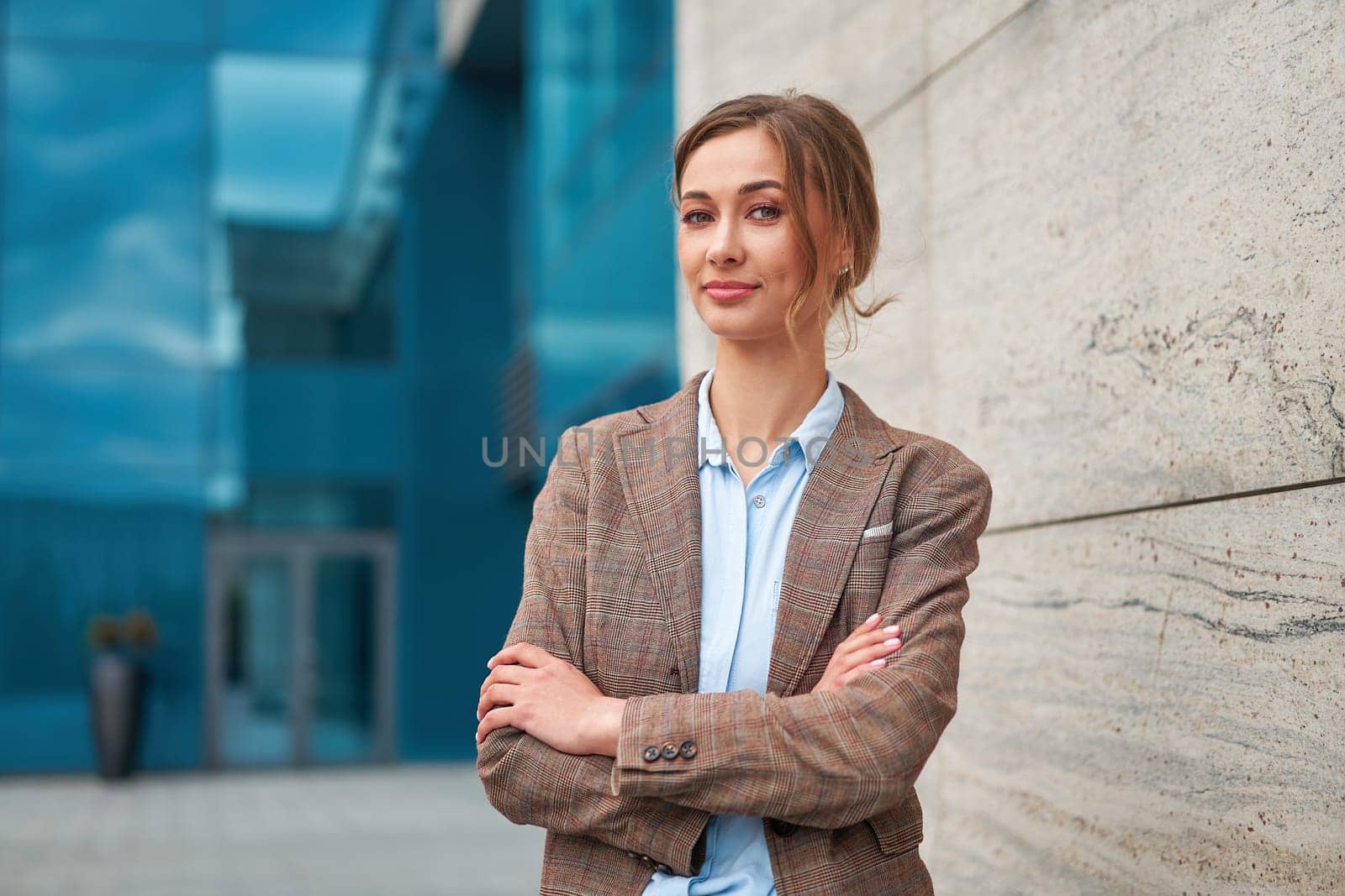 Businesswoman successful woman business person standing arms crossed outdoor corporate building exterior. Pensiv caucasian confidence professional business woman middle age by andreonegin