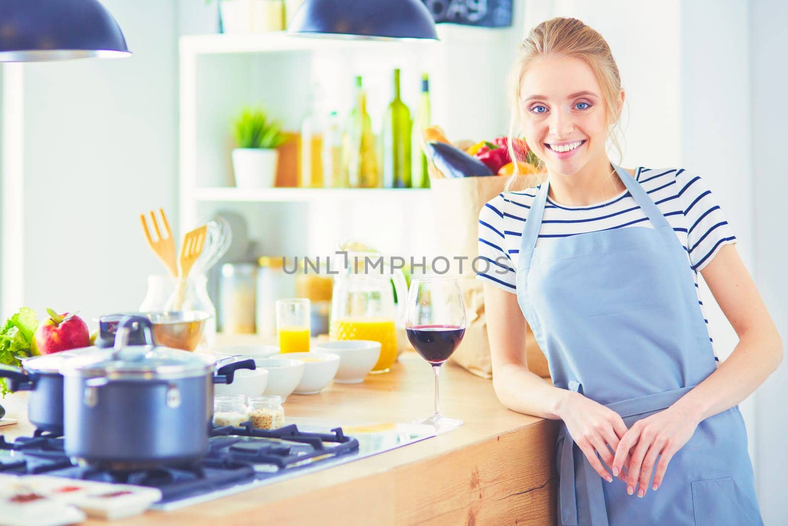 Pretty woman drinking some wine at home in kitchen.