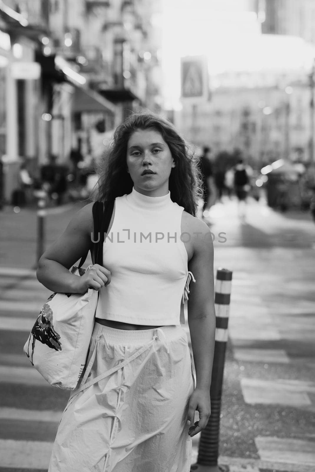 A fashionable girl in white attire with curly hair on the city streets. High quality photo