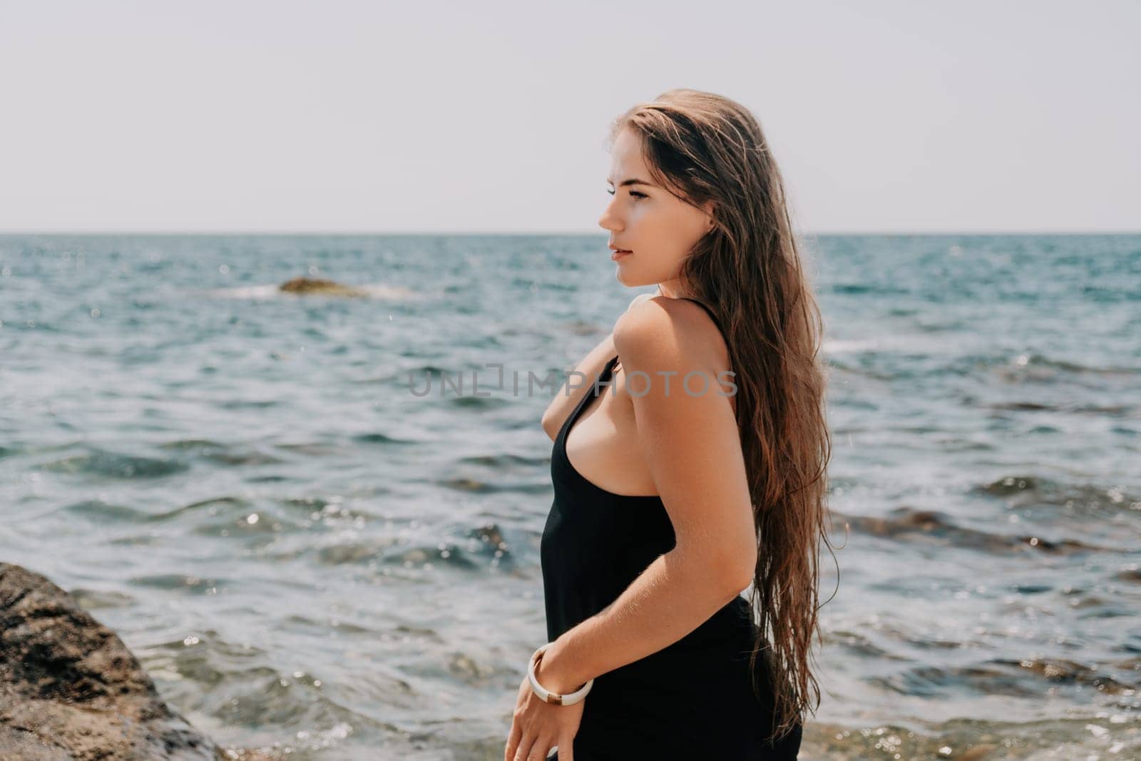 Woman summer travel sea. Happy tourist in hat enjoy taking picture outdoors for memories. Woman traveler posing on the beach at sea surrounded by volcanic mountains, sharing travel adventure journey by panophotograph