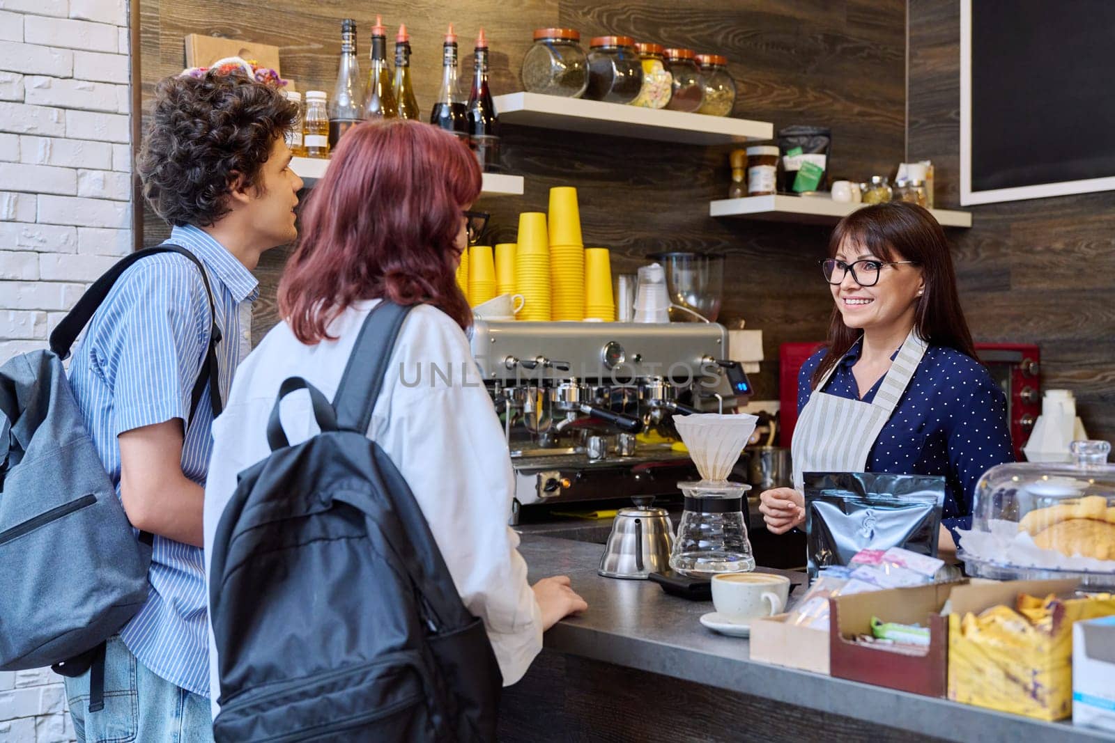 Customers of coffee shop making an order, talking to female barista cafe worker by VH-studio