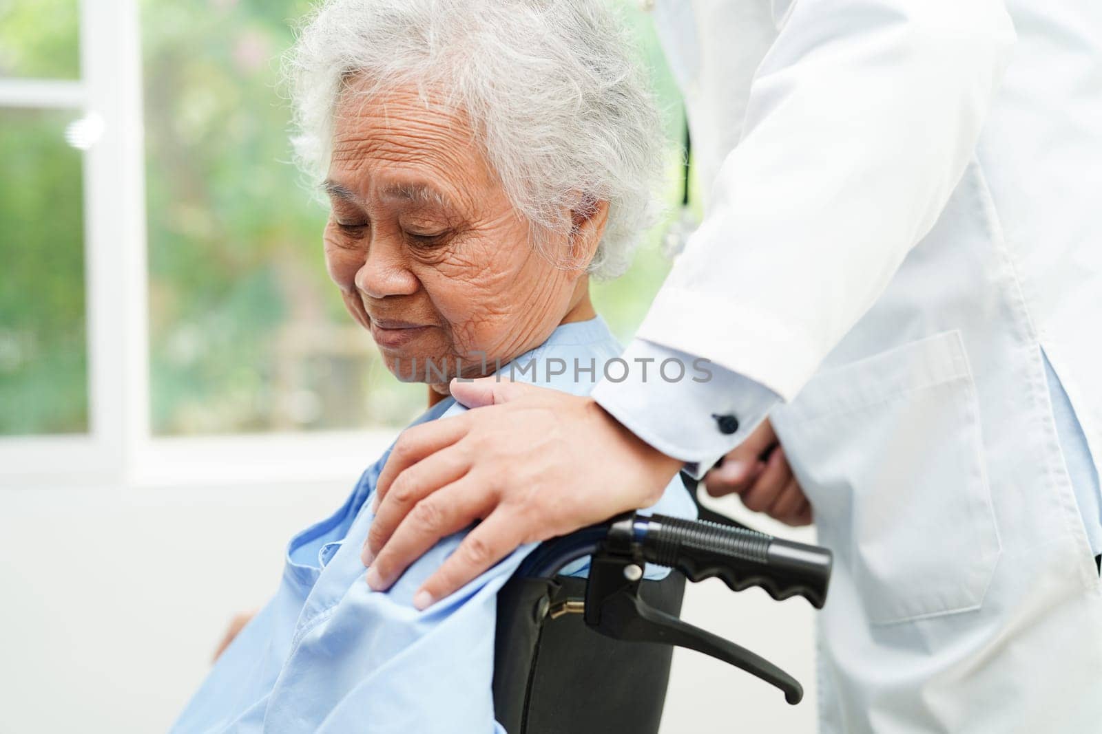 Doctor help Asian elderly woman disability patient sitting on wheelchair in hospital, medical concept.