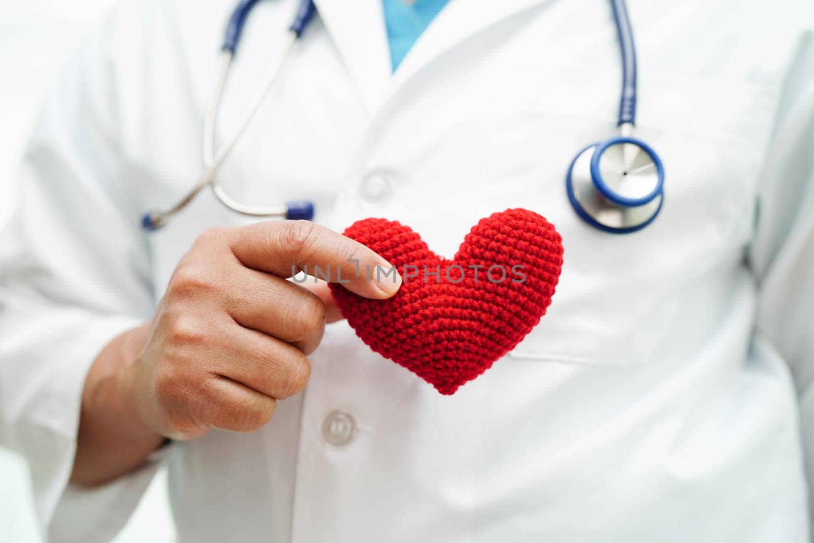 Asian woman doctor holding red heart for health in hospital.