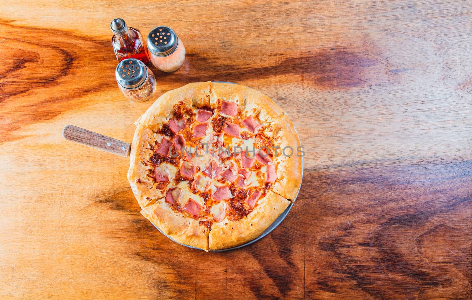 Ham pizza with cheese edge on wooden background. Top view of ham and cheese pizza on wooden table