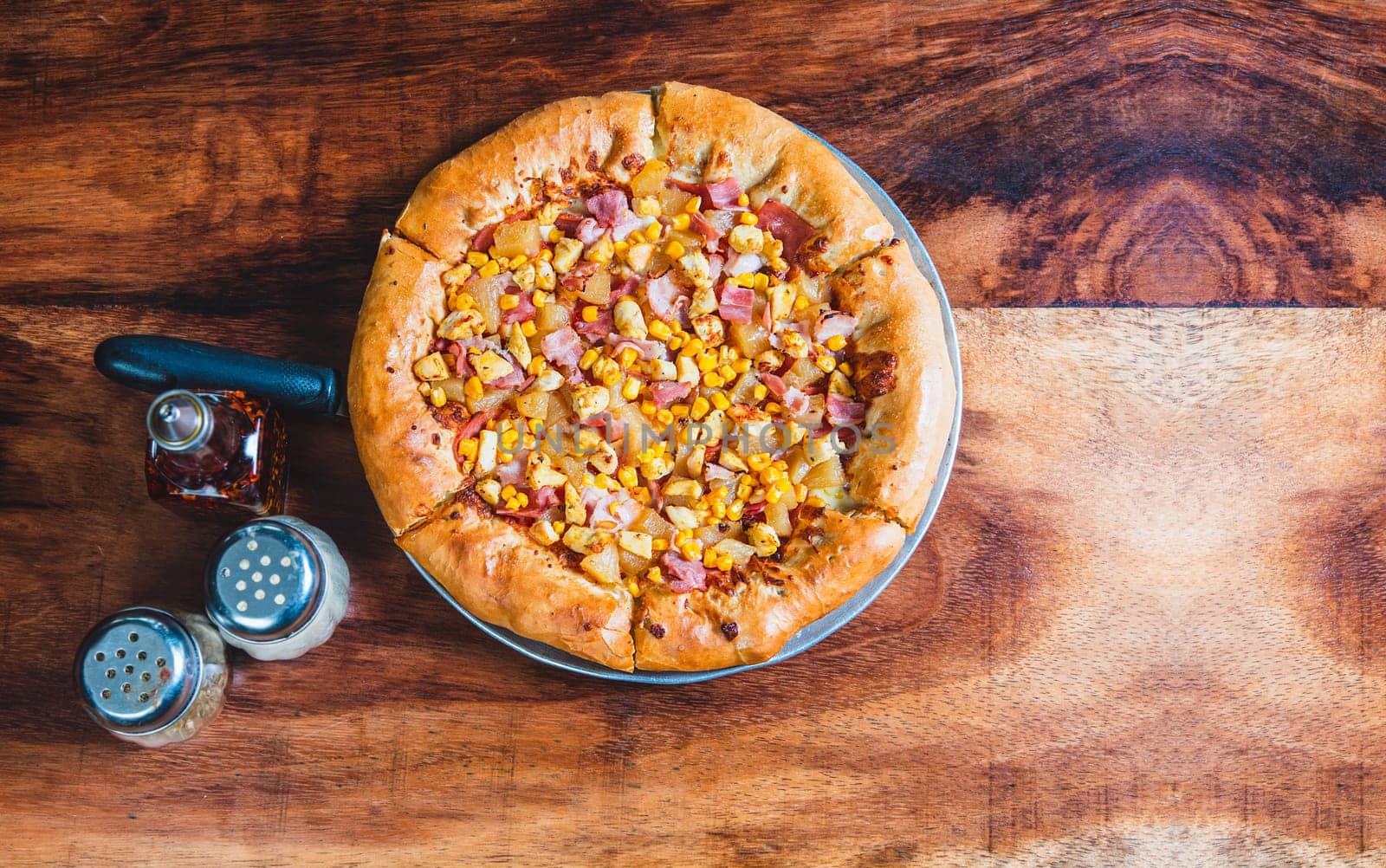 Top view of ham and corn pizza on wooden table. Ham pizza with corn on wooden background by isaiphoto