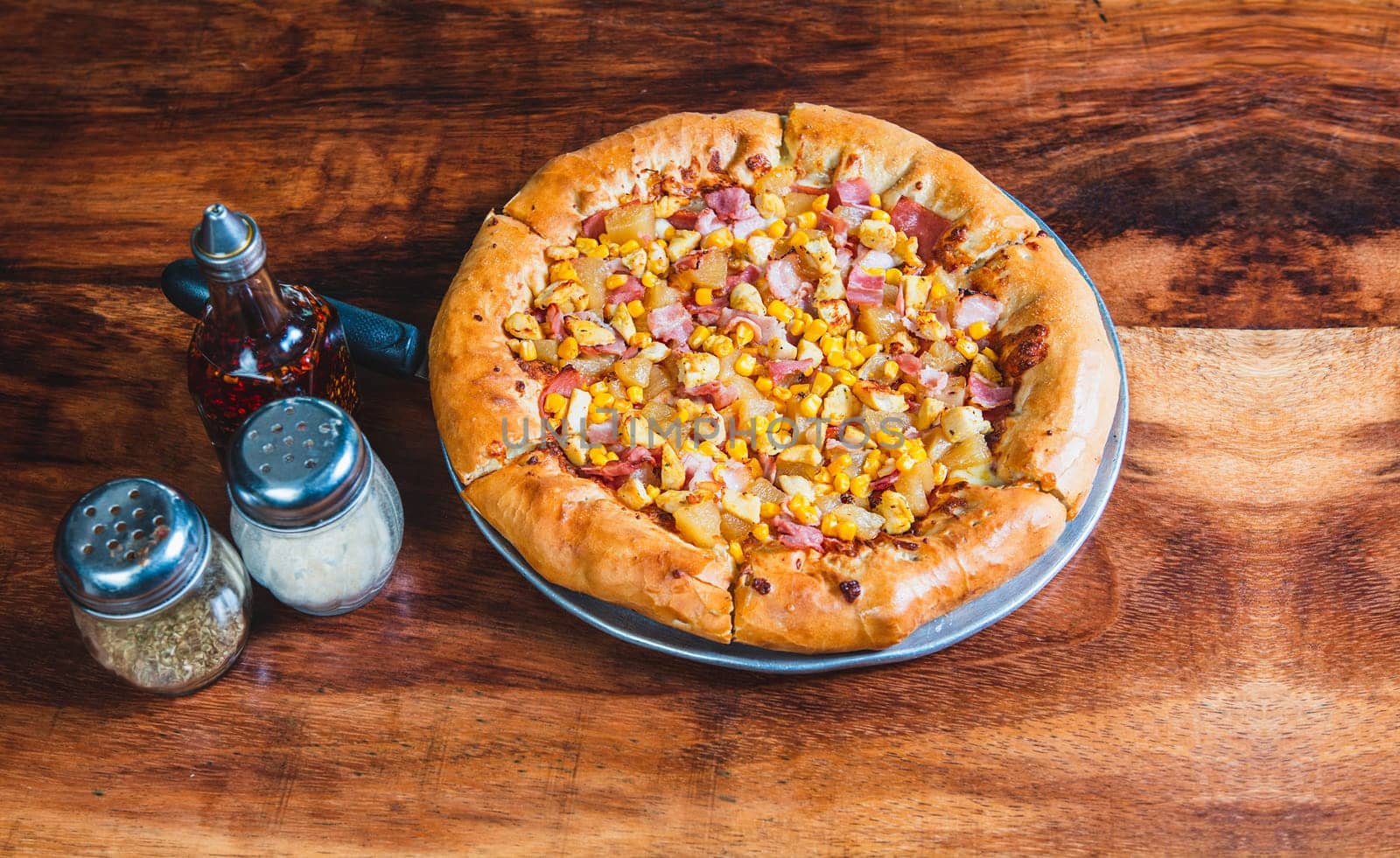 Ham pizza with corn on wooden background. Top view of ham and corn pizza on wooden table