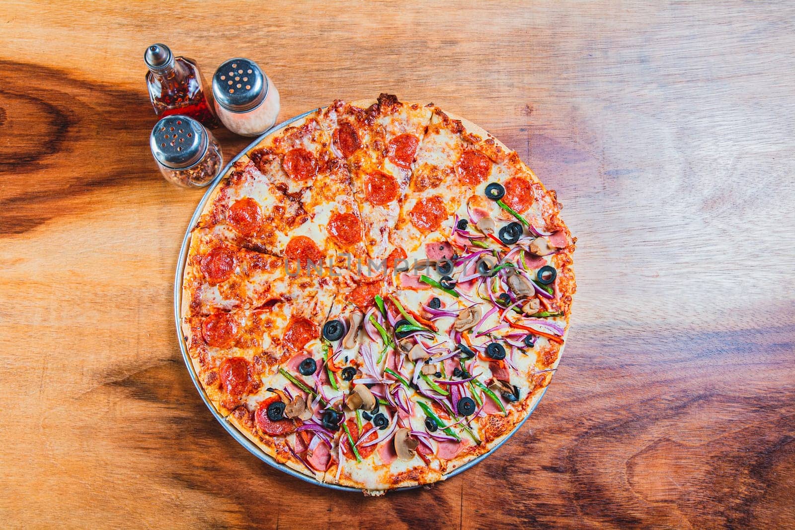 Top view of a supreme mixed pizza on wooden table. High angle view of mixed supreme pizza on wooden table by isaiphoto