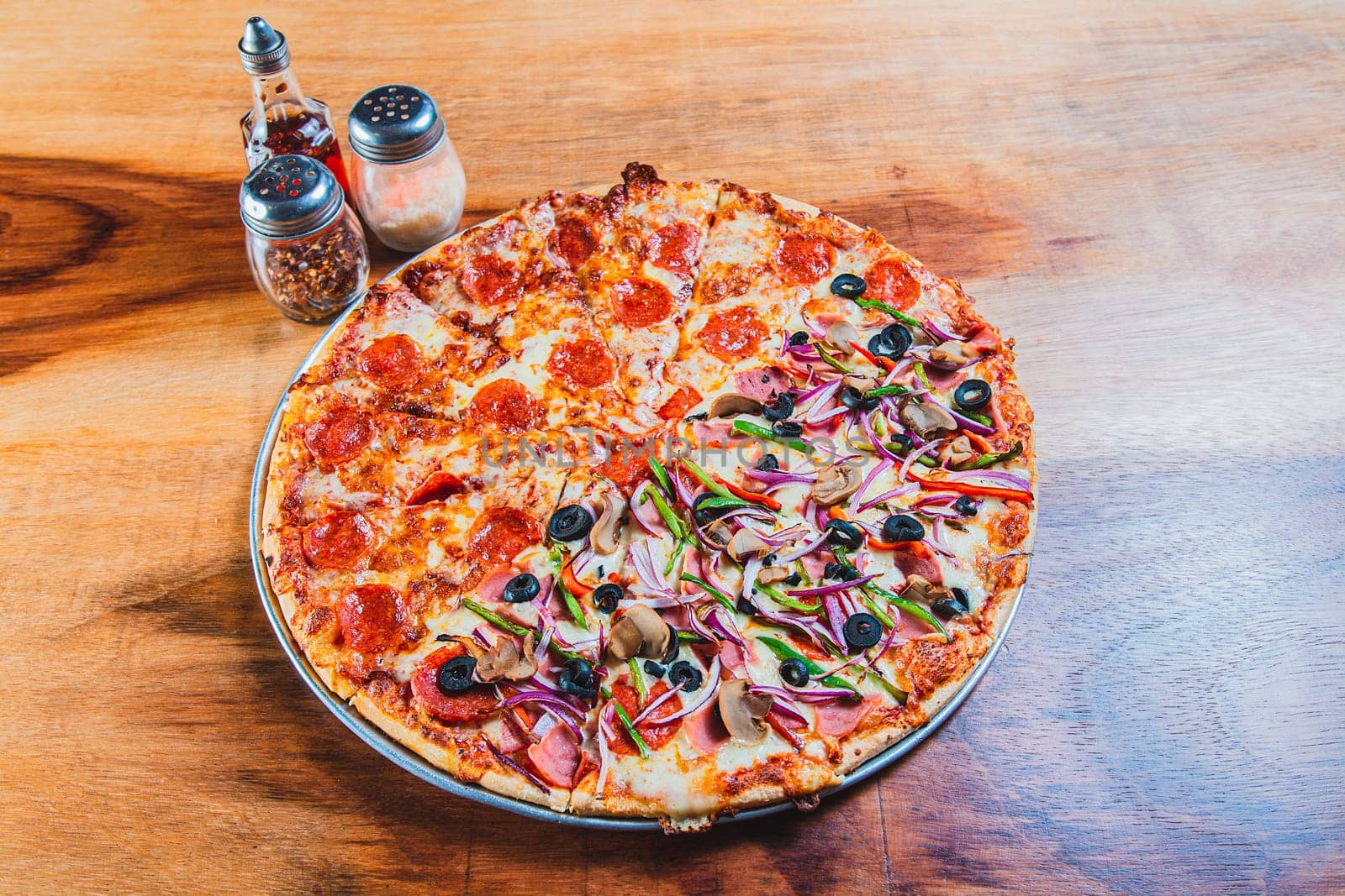 High angle view of mixed supreme pizza on wooden table. Top view of a supreme mixed pizza on wooden table by isaiphoto