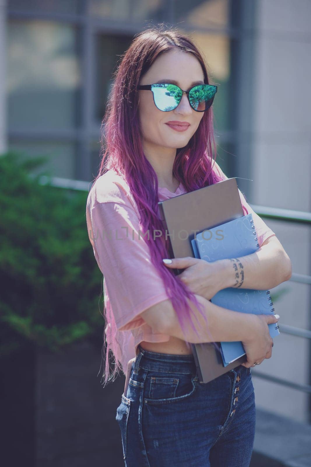 Portrait beautiful female writer dressed in casual outfit holding modern laptop in hand. Young student of faculty journalism having good mood outdoor