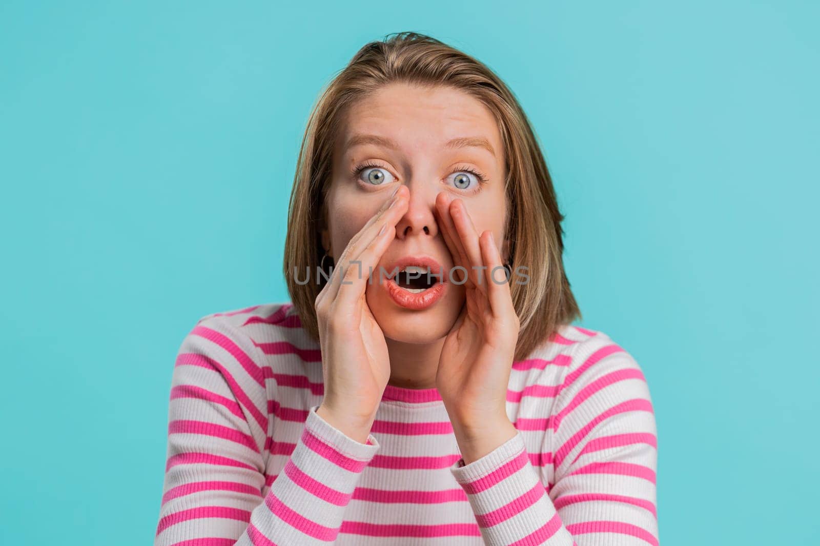 Keep my secrets, silence. Woman whisper news rumors holding hands near mouth share gossip, quiet. Girl in crop top telling interesting confidential story isolated on blue studio background. Lifestyles