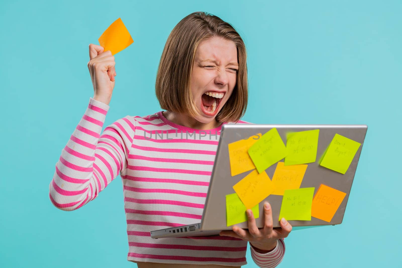 Exhausted freelancer woman with pasted sticker notes use laptop computer having concentration problem creative crisis, time out. Nervous girl confused by big routine work loading on blue background