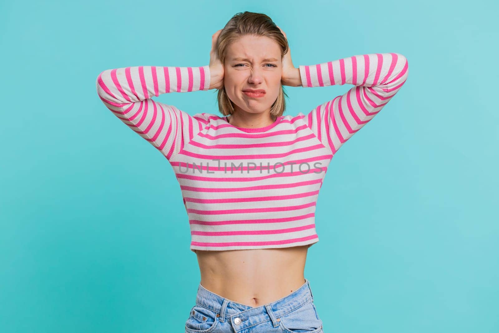 Dont want to hear and listen. Frustrated annoyed irritated woman covering ears gesturing No, avoiding advice ignoring unpleasant noise loud voices. Girl in crop top isolated alone on blue background