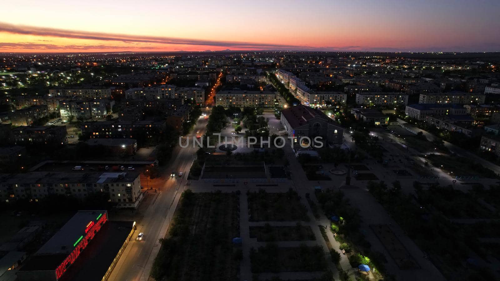 The outskirts of the city. There are old houses, garages and fences. In the distance, you can see the TV tower and the city. Swifts fly. The sky is shimmering purple-blue. Shooting from a drone.