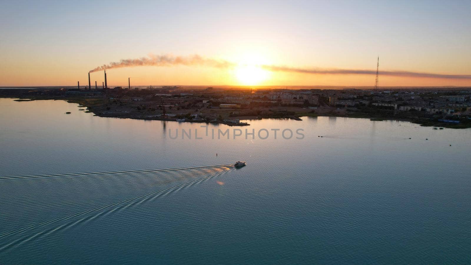 The boat sails in the bay at sunset near the city by Passcal