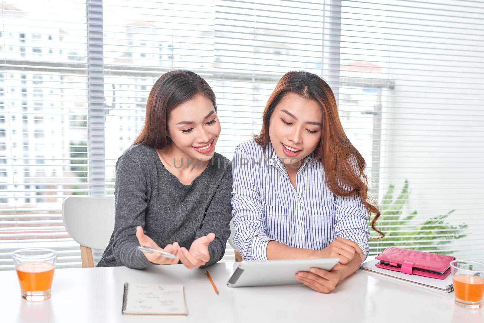 Happy young businesswoman talking to her colleague