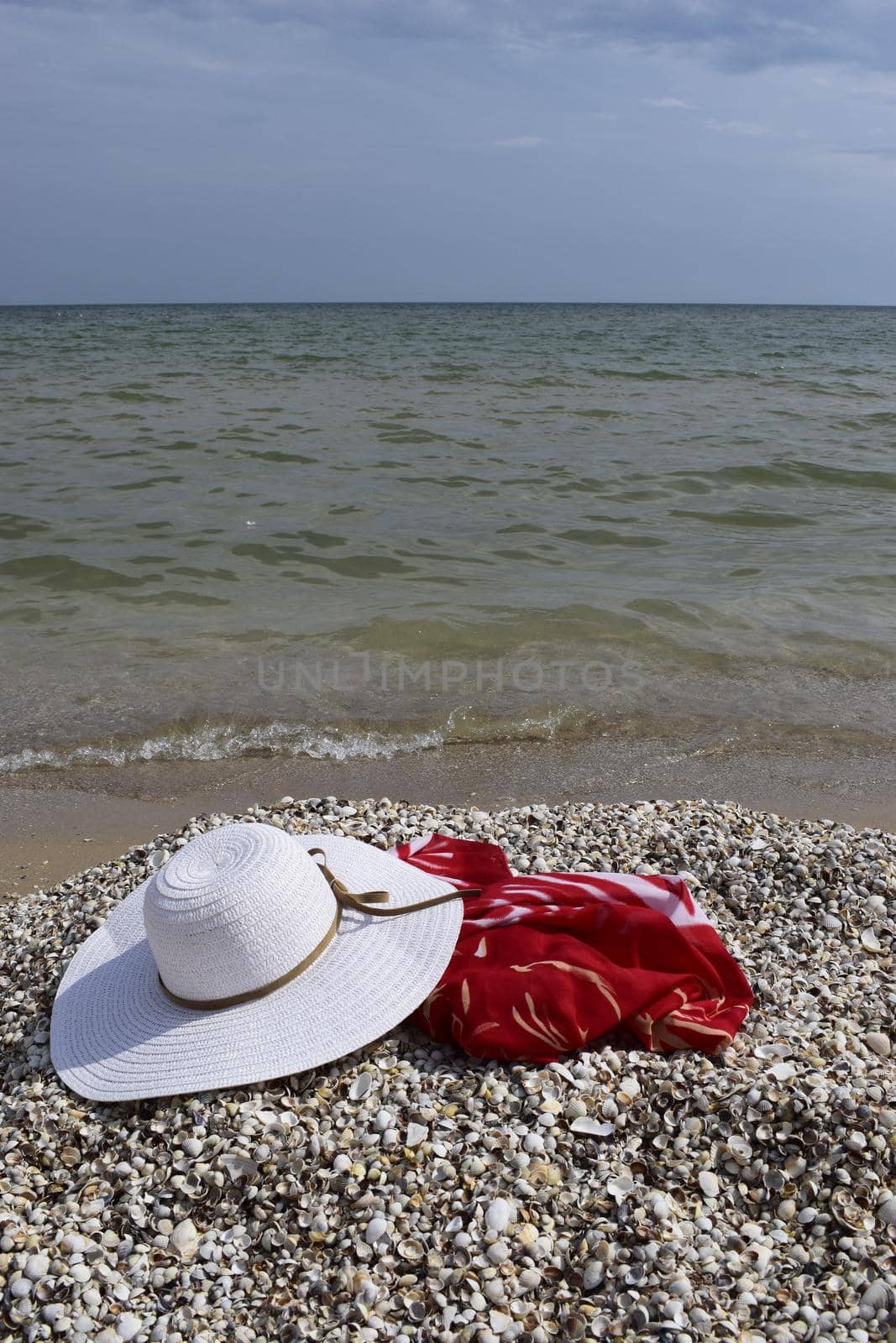 Vintage summer straw beach hat and pareo on the seashore. Accessories for relaxing on the beach. Summer lifestyle. Vacation mood.