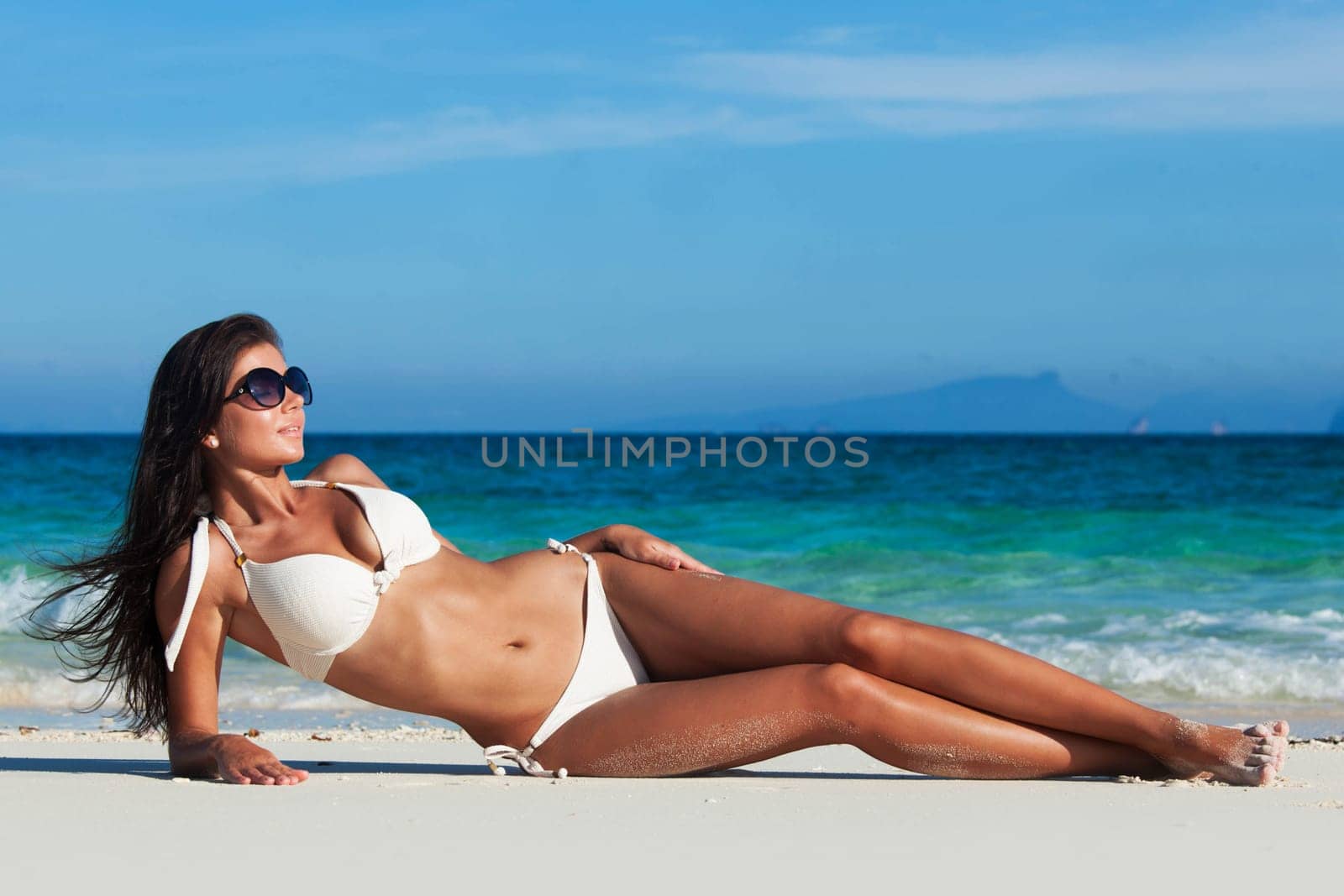 Young woman in bikini laying by tropical sea