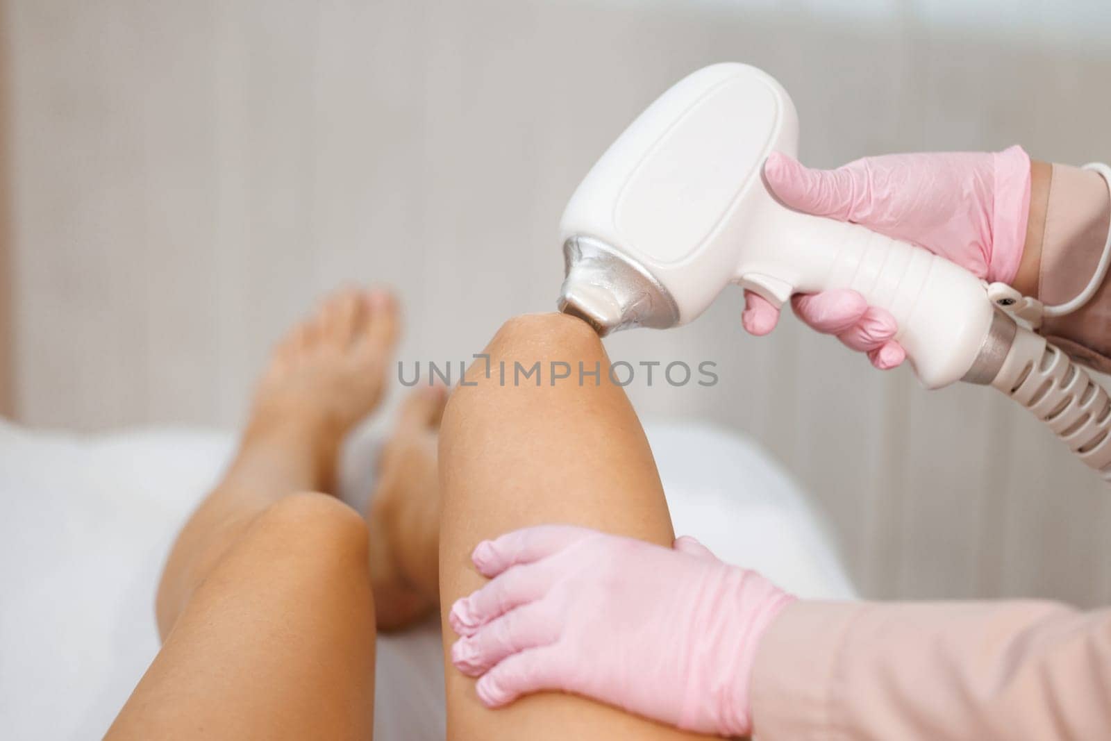 Cosmetology hair removal procedure from therapist in a cosmetic spa beauty clinic. Laser epilation. Cosmetology and SPA concept. Midsection of female beautician using laser machine on customer's leg.