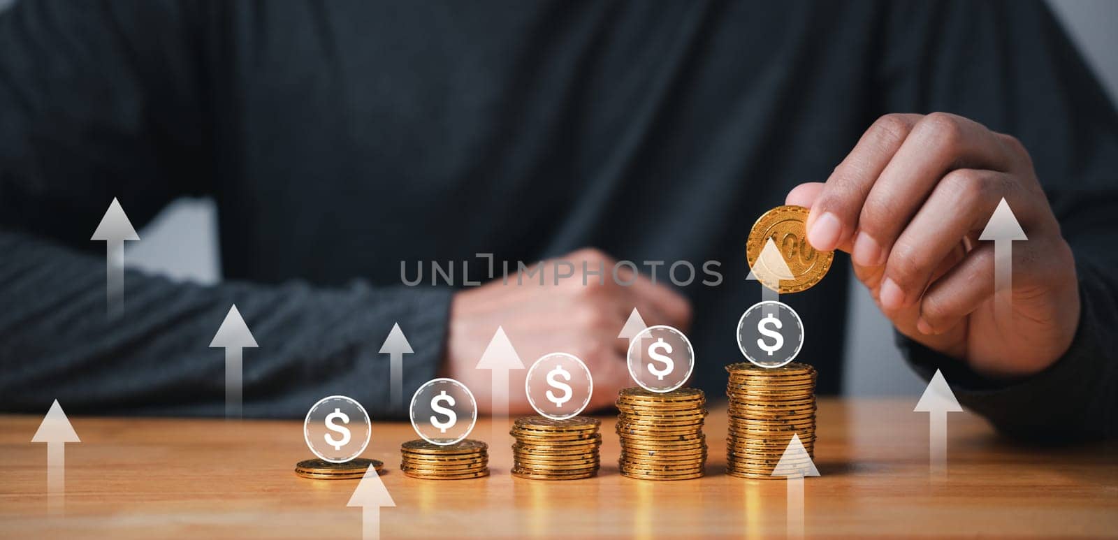 Hand of businessman holding coin on stack of coins with rising graph by Sorapop