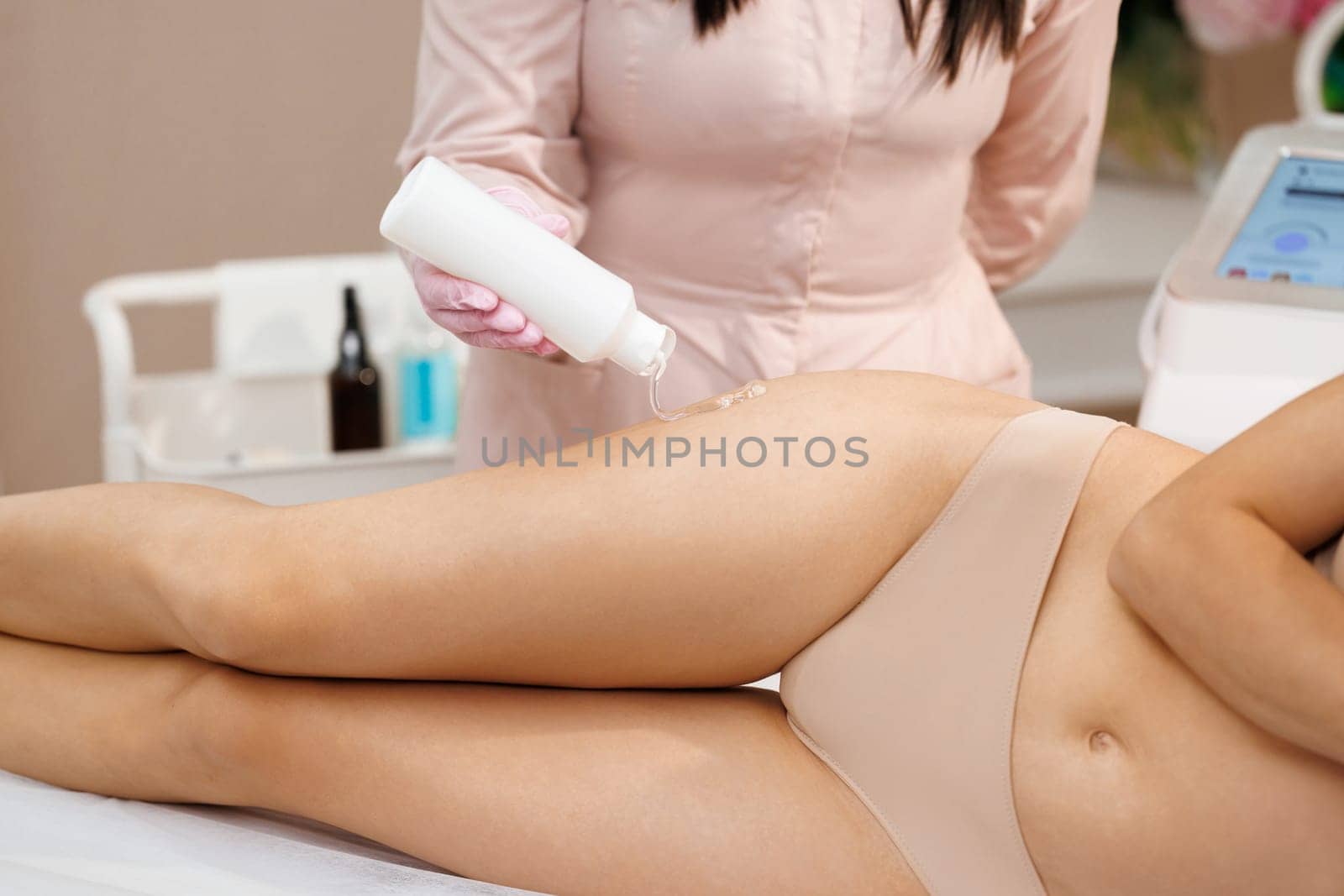 Beautician applying gel on female leg before epilation. Cosmetologist preparing woman skin for laser hair removal treatment in cosmetology clinic. Applying conductive gel by uflypro